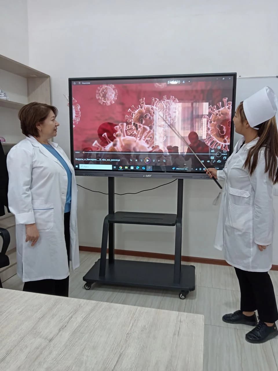 O‘qituvchi va talaba interaktiv ekranda mikrobiologiya mavzusini ko‘rib chiqmoqda